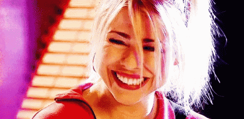 a woman is smiling and making a funny face while wearing a red shirt and earrings .