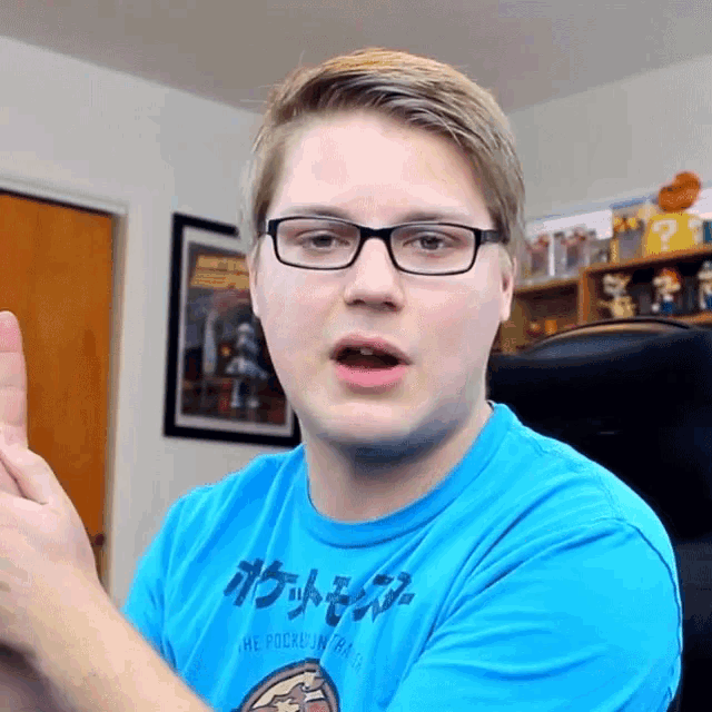 a man wearing glasses and a blue shirt that says ' pokemon ' on the front
