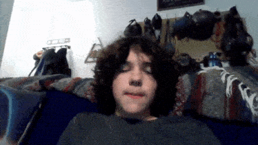 a young boy with curly hair is laying on a couch with his eyes closed