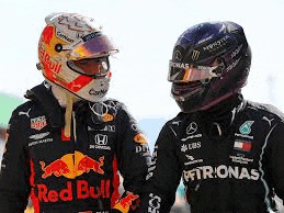 two racing drivers are shaking hands while wearing helmets and jackets .