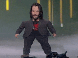 keanu reeves is standing on a stage wearing a suit and a black shirt .