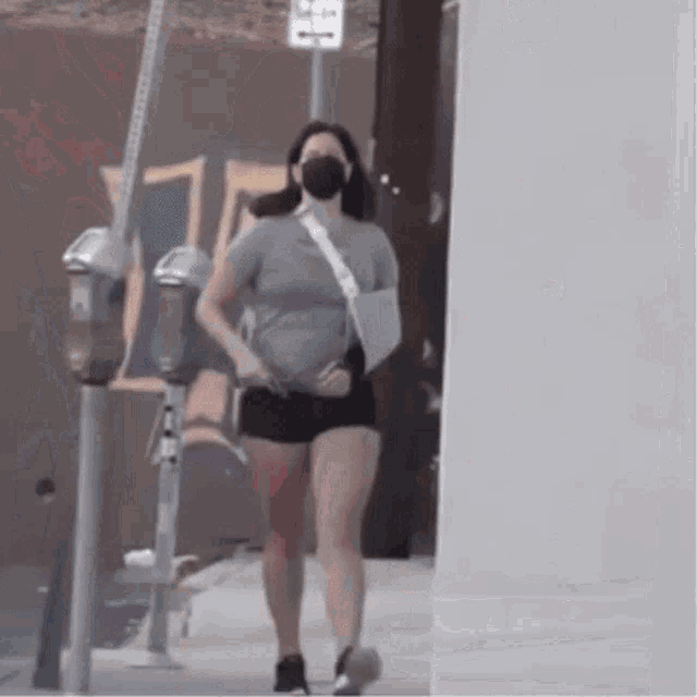 a woman wearing a mask is walking down the street