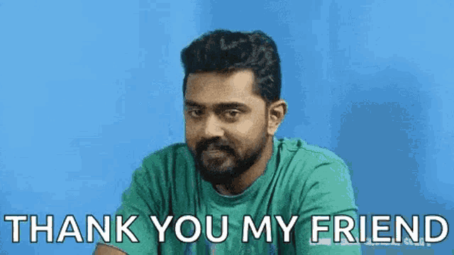 a man with a beard is sitting in front of a blue background and saying thank you my friend .