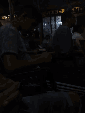 a man sits in front of a sign that says cafe