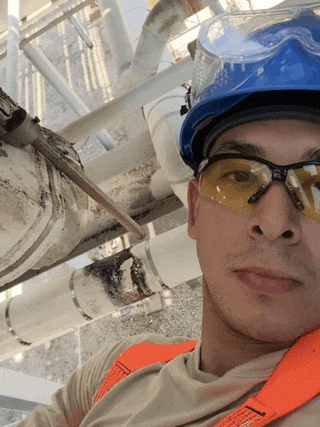 a man wearing safety glasses and a hard hat takes a selfie