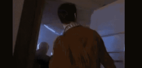 a blurry picture of a man in a brown jacket standing in a room .