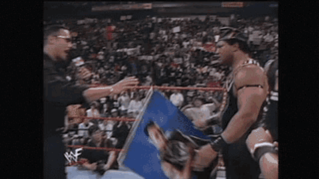 a man in a wrestling ring is talking to another man while holding a sign that says wwe
