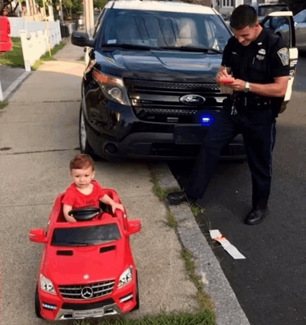 a police officer writes a ticket to a child in a toy car