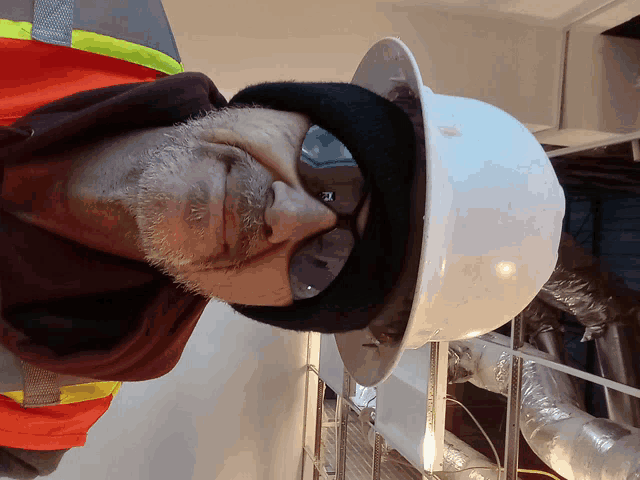 a man wearing a hard hat and safety glasses with the letter t on his face