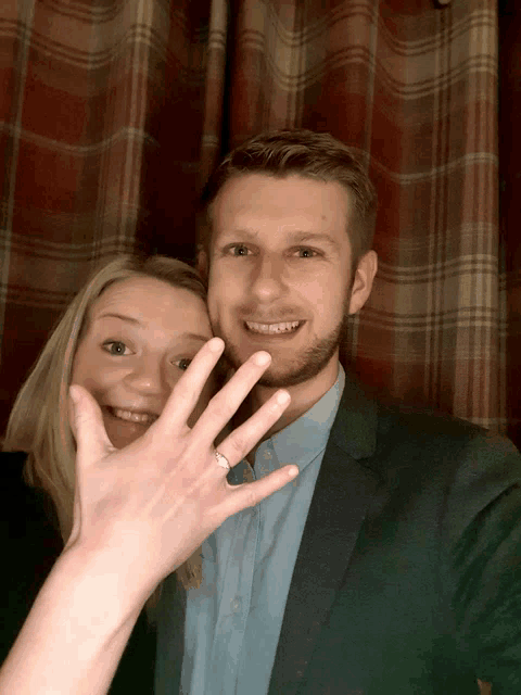 a man and a woman are posing for a picture and the woman is showing off her engagement ring