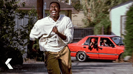 a man running in front of a red car