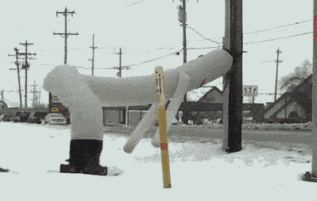 a statue of a man standing in the snow next to a sign that says ' a / t '