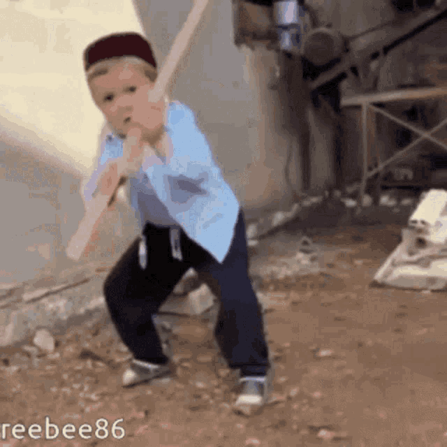 a young boy is holding a large wooden stick in his hand while wearing a hat and a blue shirt ..