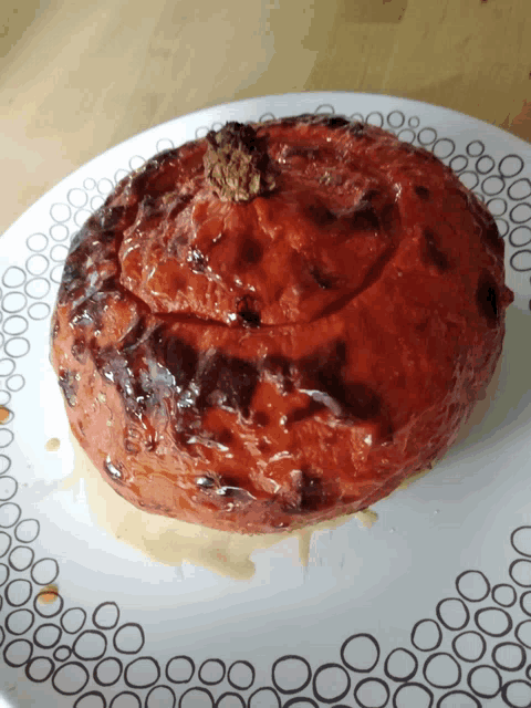 a white plate with circles on it has a roasted tomato on it