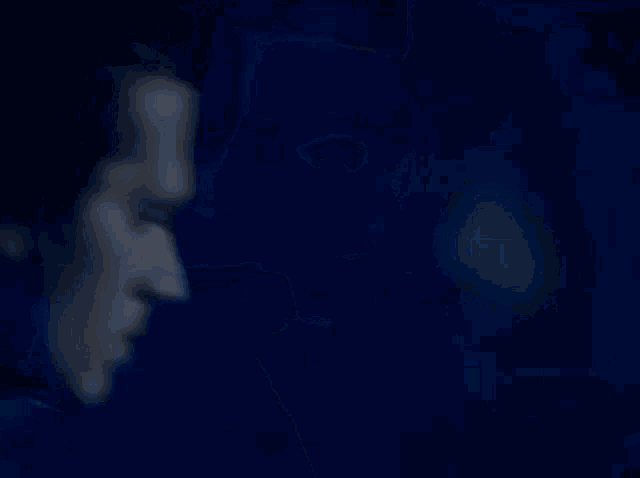a blurry picture of a man 's face in a dark room with a blue light behind him .