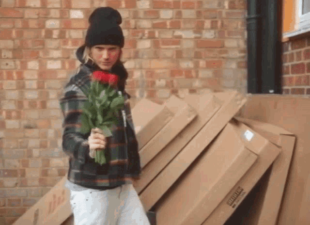 a man holding a bouquet of red roses in front of a stack of cardboard boxes with the word winners on it