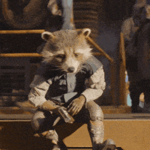 a raccoon is sitting on a box with a gun in its hands