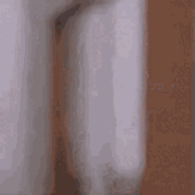 a blurry picture of a man peeking out from behind a wall .