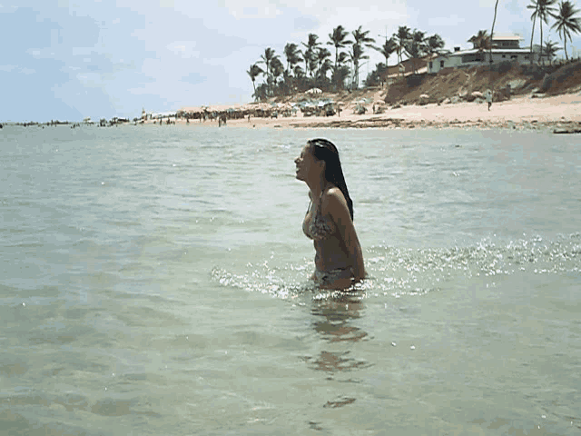 a woman in a bikini is standing in a body of water