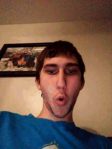 a man wearing a blue shirt is standing in front of a framed picture