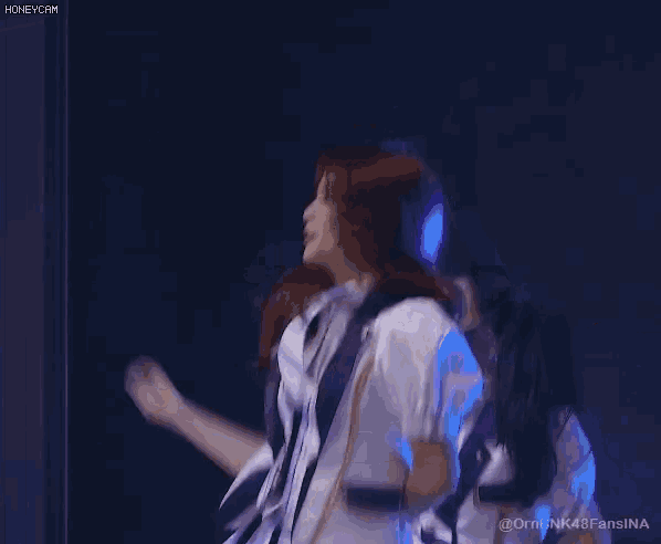 a woman in a white dress is dancing on a stage in front of a blue background ..