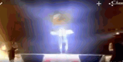 a blurred image of a person standing on a stage with a blue background