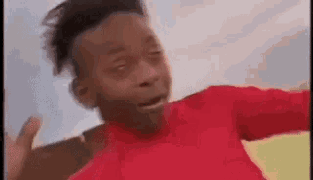 a young boy in a red shirt is jumping in the air .