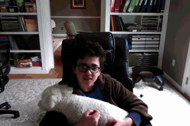 a boy sitting in a chair holding a stuffed animal with the letter r on the back of it