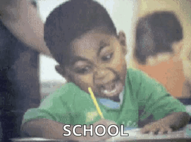 a young boy is sitting at a desk in a classroom with a pencil in his mouth and the word school is visible .