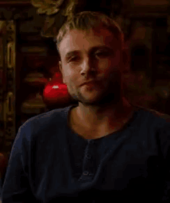 a man with a beard wearing a blue shirt is looking at the camera