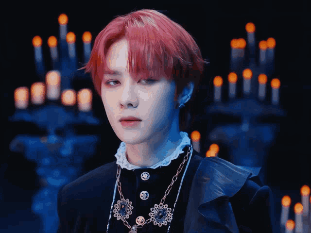 a man with red hair is wearing a black jacket and necklace