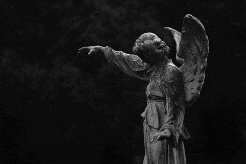 a black and white photo of a statue of an angel with her arms outstretched .