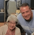 a man and an older woman are posing for a picture together in a kitchen .