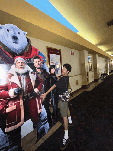 a man stands in front of a cardboard cut out of santa and a polar bear