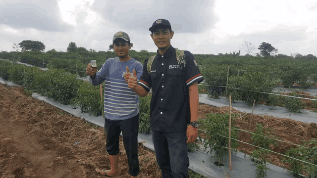 two men standing in a field one of whom is wearing a shirt that says ' agricultural scientist ' on it