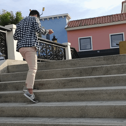 a person walking up a set of stairs in front of a pink building