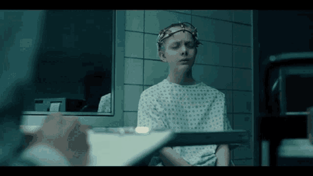 a young girl in a hospital gown is sitting at a table