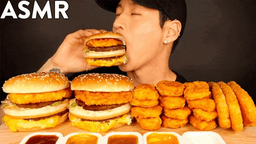 a man is eating a hamburger surrounded by nuggets and sauces