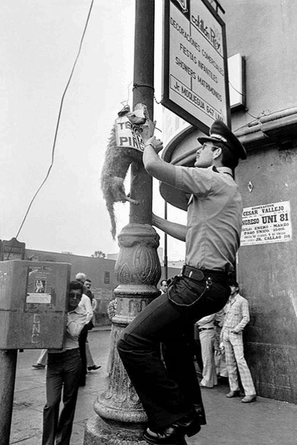 a black and white photo of a police officer with a squirrel hanging from a pole