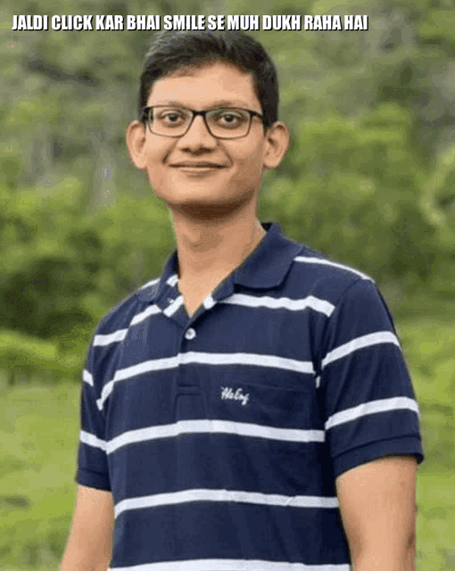 a young man wearing glasses and a blue and white striped shirt stands in front of a green forest