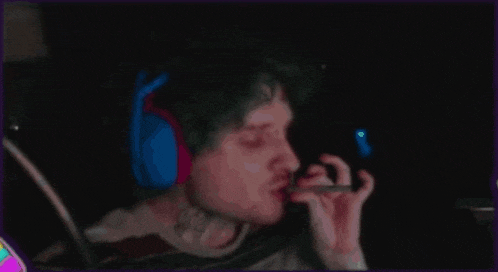 a person wearing headphones is smoking a cigarette in the dark