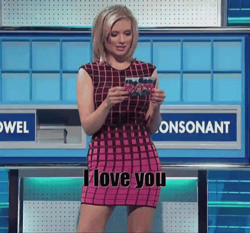 a woman in a pink dress is standing in front of a sign that says i love you