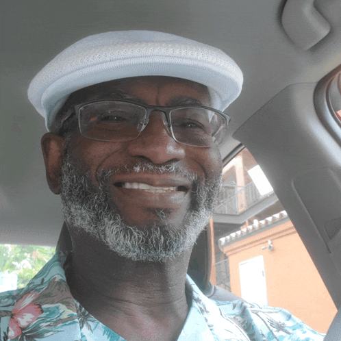 a man wearing glasses and a hat is smiling in a car