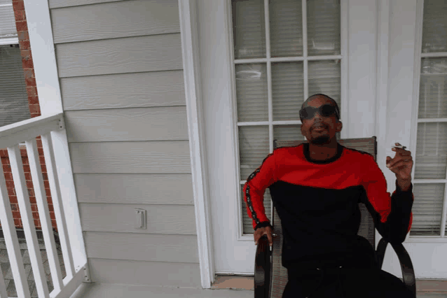 a man in a red and black shirt is smoking a cigarette