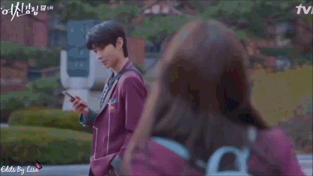 a man in a purple jacket is holding a cell phone next to a woman in a white dress