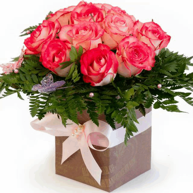 a bouquet of pink roses in a brown box with a white ribbon and pearls