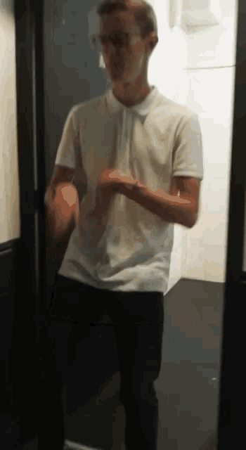 a man in a white shirt and black pants stands in a doorway