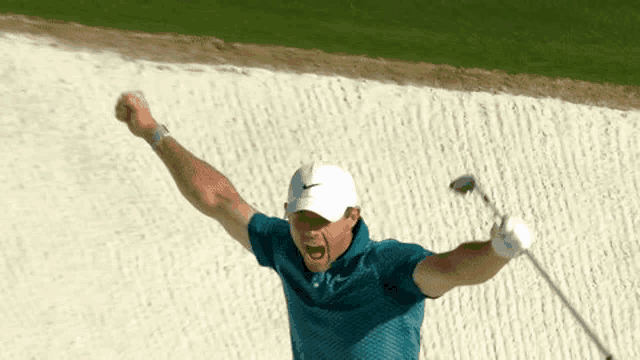 a man in a blue shirt is holding a golf club in his hand and celebrating .