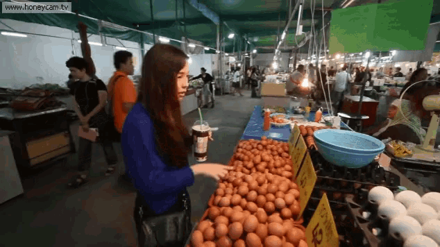 a woman stands in front of a display of eggs with a sign that says ' eggs ' on it