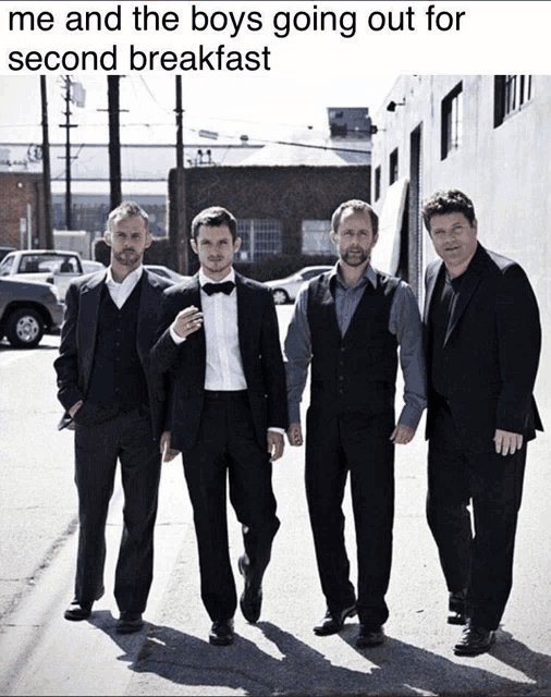 a group of men in suits and bow ties are walking down a street